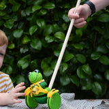 Child pushing the Nic Toys frog king push along toy. Green frog with yellow felt details and gold bell. 