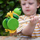 Child holding the Nic Toys frog king push along toy. Green frog with yellow felt details and gold bell. 