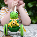 Child holding the stick on the Nic Toys frog king push along toy. Green frog with yellow felt details and gold bell. 