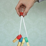 A adult hand holding the Nic Toys wooden grasping keyring set available at Babipur against a green decorative background.