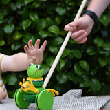 Children playing with the Nic Toys frog king push along toy. Green frog with yellow felt details and gold bell. 