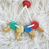 A close up of the Nic Toys wooden grasping keyring set available at Babipur on a white decorative blanket showing the different shaped keys.