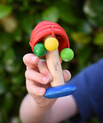 Nic mushroom wooden rattle toy in a child's hand.