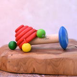 Nic mushroom wooden rattle toy placed on a wooden surface. 