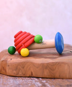 Nic mushroom wooden rattle toy placed on a wooden surface. 