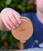 Nic Toys wooden rolling rattle in a child's hand. Roll along rattle with multicoloured beads.