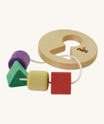 Nic Toys wooden threaded shape sorted. Features a disk with a keyhole shape cut out in the middle with a piece of thread feeding through different coloured blocks in different shapes 
