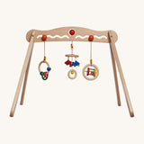 A Nic Toys wooden baby trainer available at Babipur. Features 3 grasping toys that can be swapped over  and hangs above when a baby is lying underneath