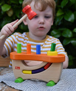 Child hammering the cylinder pieces into the Nic wooden pounding bench hammering toy.
