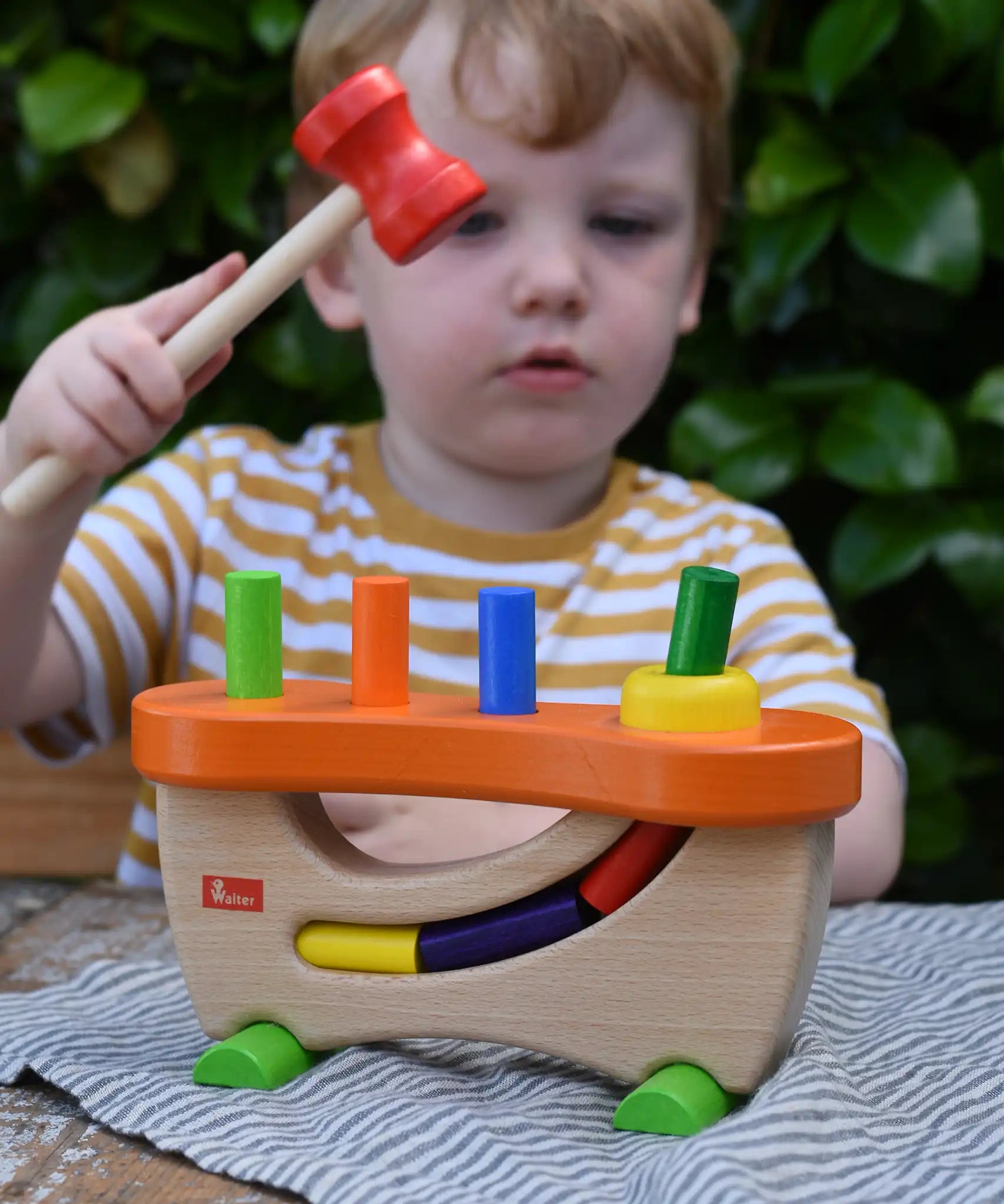 Child hammering the cylinder pieces into the Nic wooden pounding bench hammering toy.