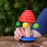Nic mushroom wooden rattle toy in a child's hand.