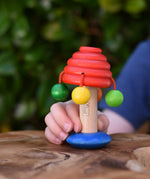Nic mushroom wooden rattle toy in a child's hand.