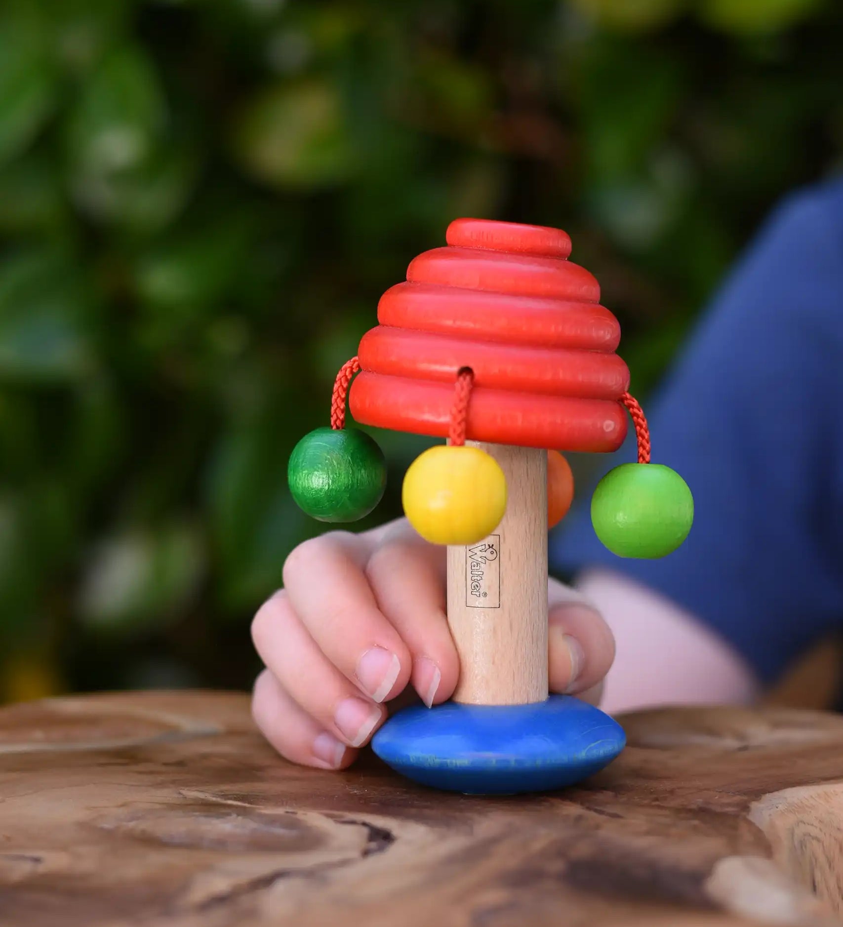 Nic mushroom wooden rattle toy in a child's hand.