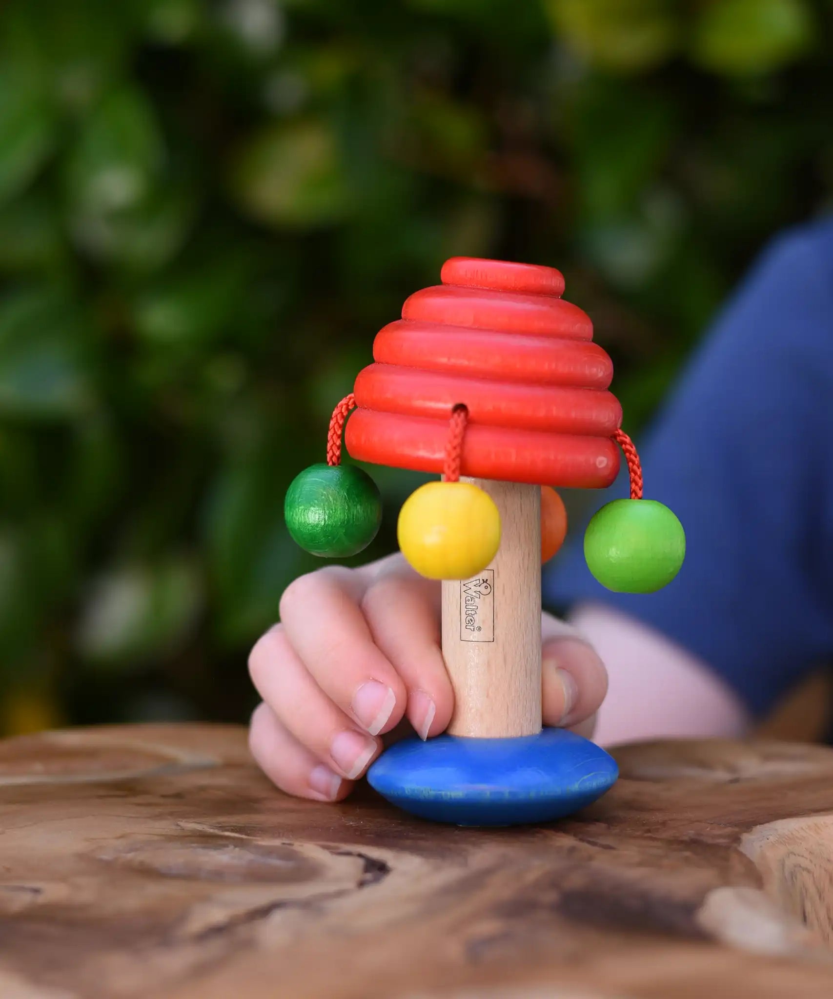 Nic mushroom wooden rattle toy in a child's hand.