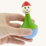 An adult hand holding the Nic toys wooden gnome tumbler available at Babipur showing the size.