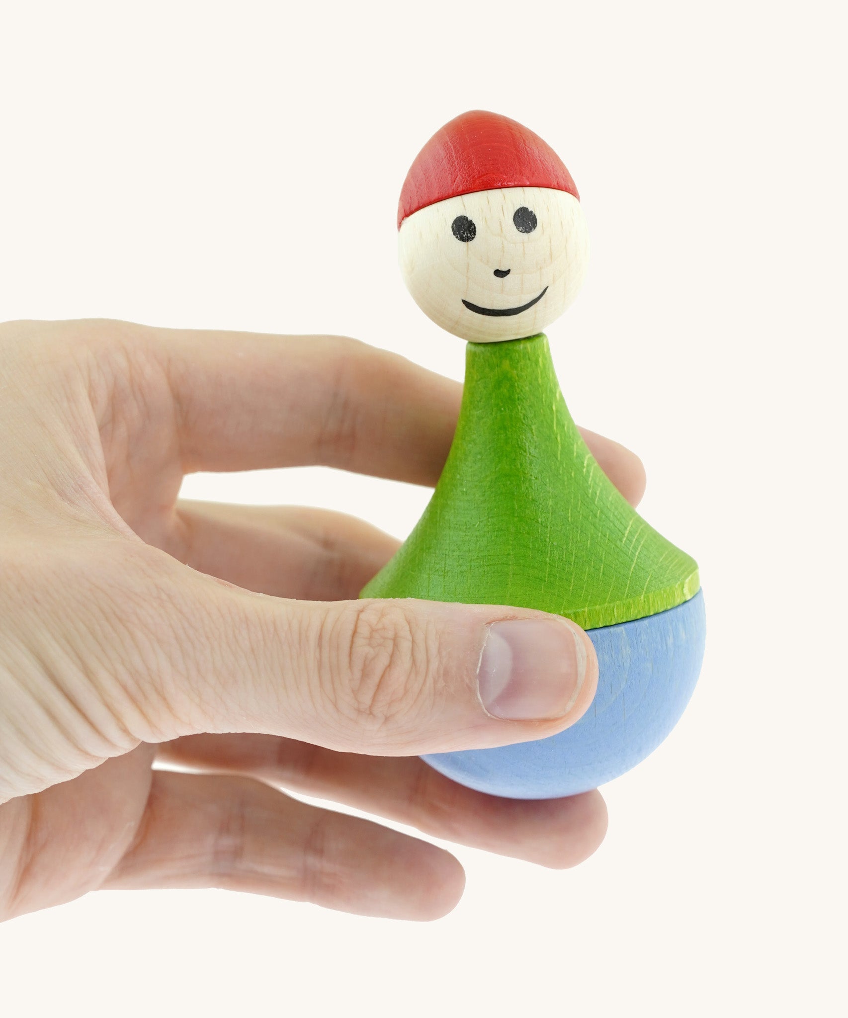 An adult hand holding the Nic toys wooden gnome tumbler available at Babipur showing the size.