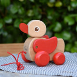 Nic waggle duck pull along wooden toy placed on a grey striped cloth.