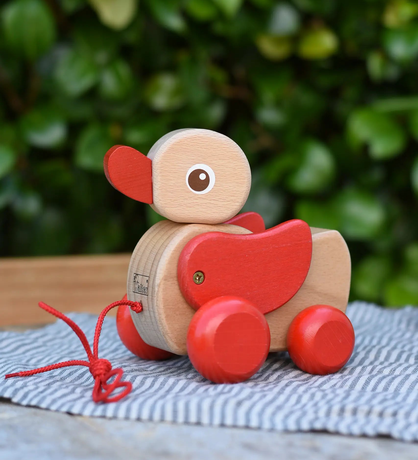 Nic waggle duck pull along wooden toy placed on a grey striped cloth.