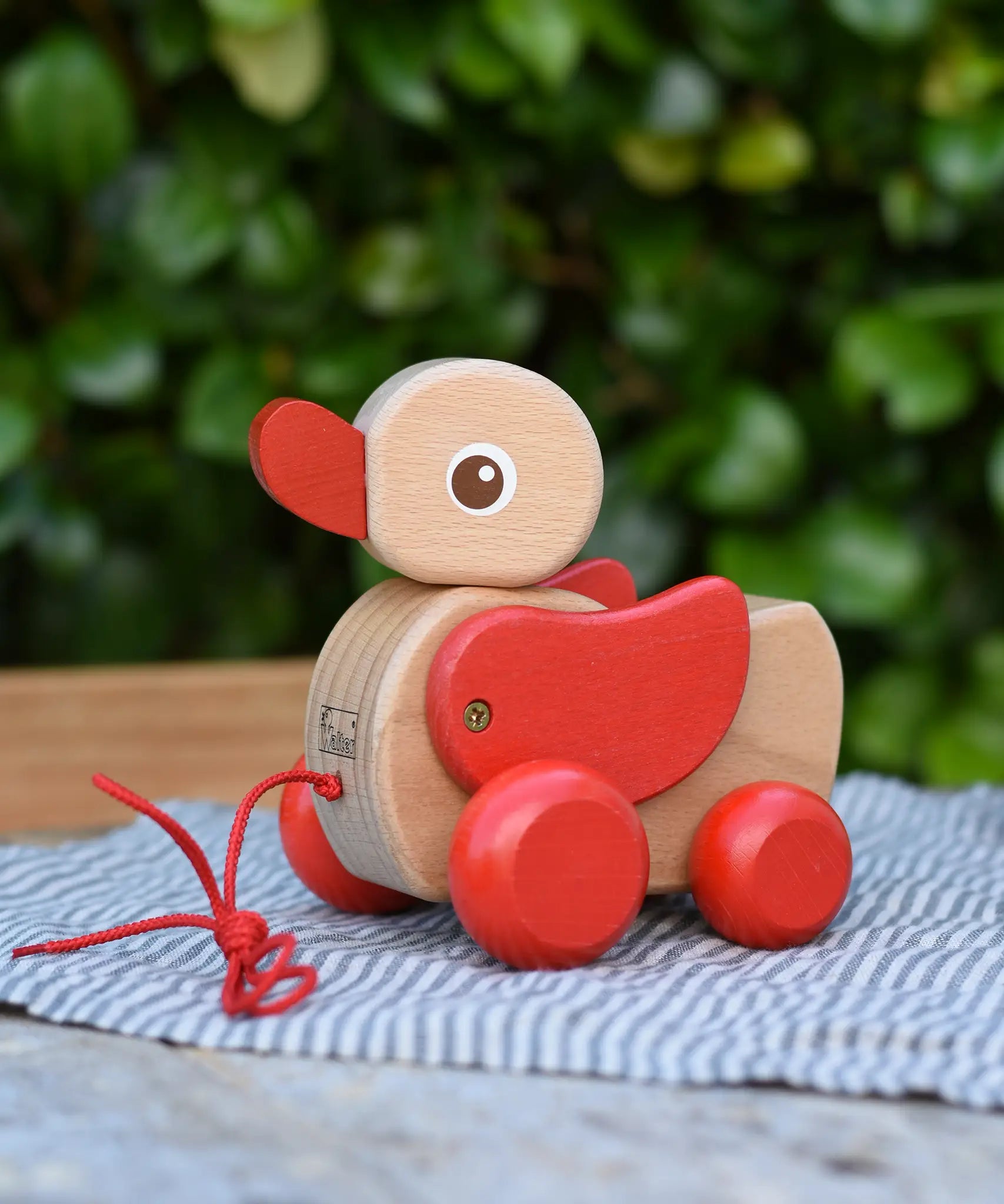 Nic waggle duck pull along wooden toy placed on a grey striped cloth.