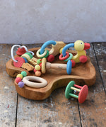 Collection of Nic organic wooden baby toys placed on a wooden dish. Wooden baby toys perfectly sized for little hands to grasp. 