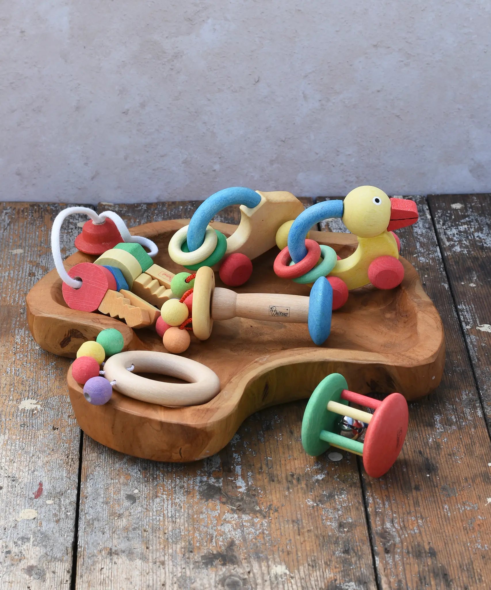 Collection of Nic organic wooden baby toys placed on a wooden dish. Wooden baby toys perfectly sized for little hands to grasp. 