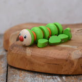 Nic Willy the centipede green wooden baby toy placed on a wooden surface. 