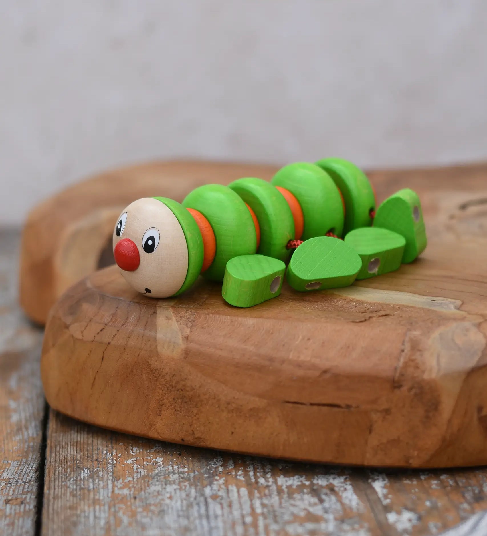 Nic Willy the centipede green wooden baby toy placed on a wooden surface. 