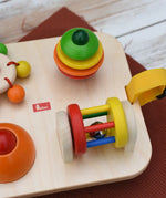 Close up of the Nic Wooden Baby Game busy Board with 4 four activities. Spin the carousel, squeaky button, rattling tree top and roller.