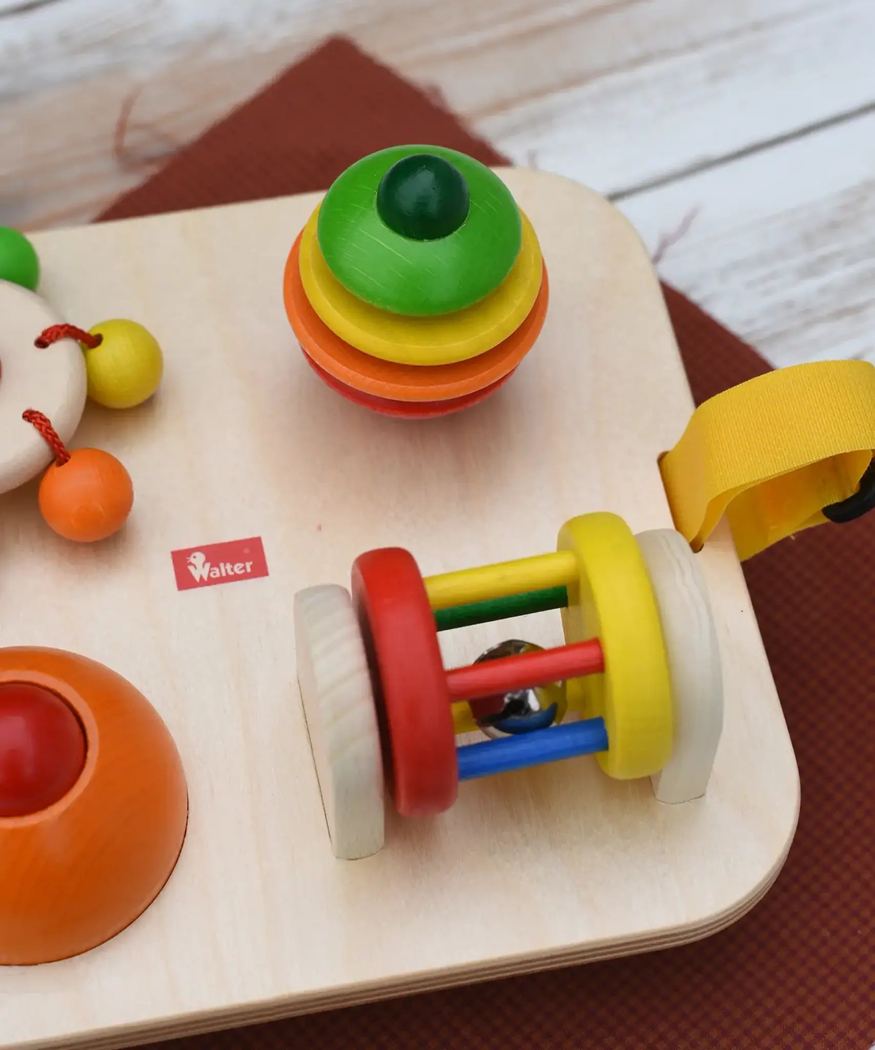 Close up of the Nic Wooden Baby Game busy Board with 4 four activities. Spin the carousel, squeaky button, rattling tree top and roller.