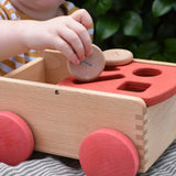 Child posting a Grapat coin into the long slot on the Nic wooden carriage shape sorter pull along toy.