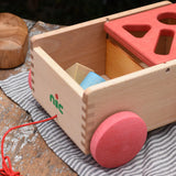 Nic wooden carriage shape sorter pull along toy shown with the blocks inside in the uncovered part. 