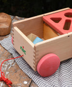 Nic wooden carriage shape sorter pull along toy shown with the blocks inside in the uncovered part. 