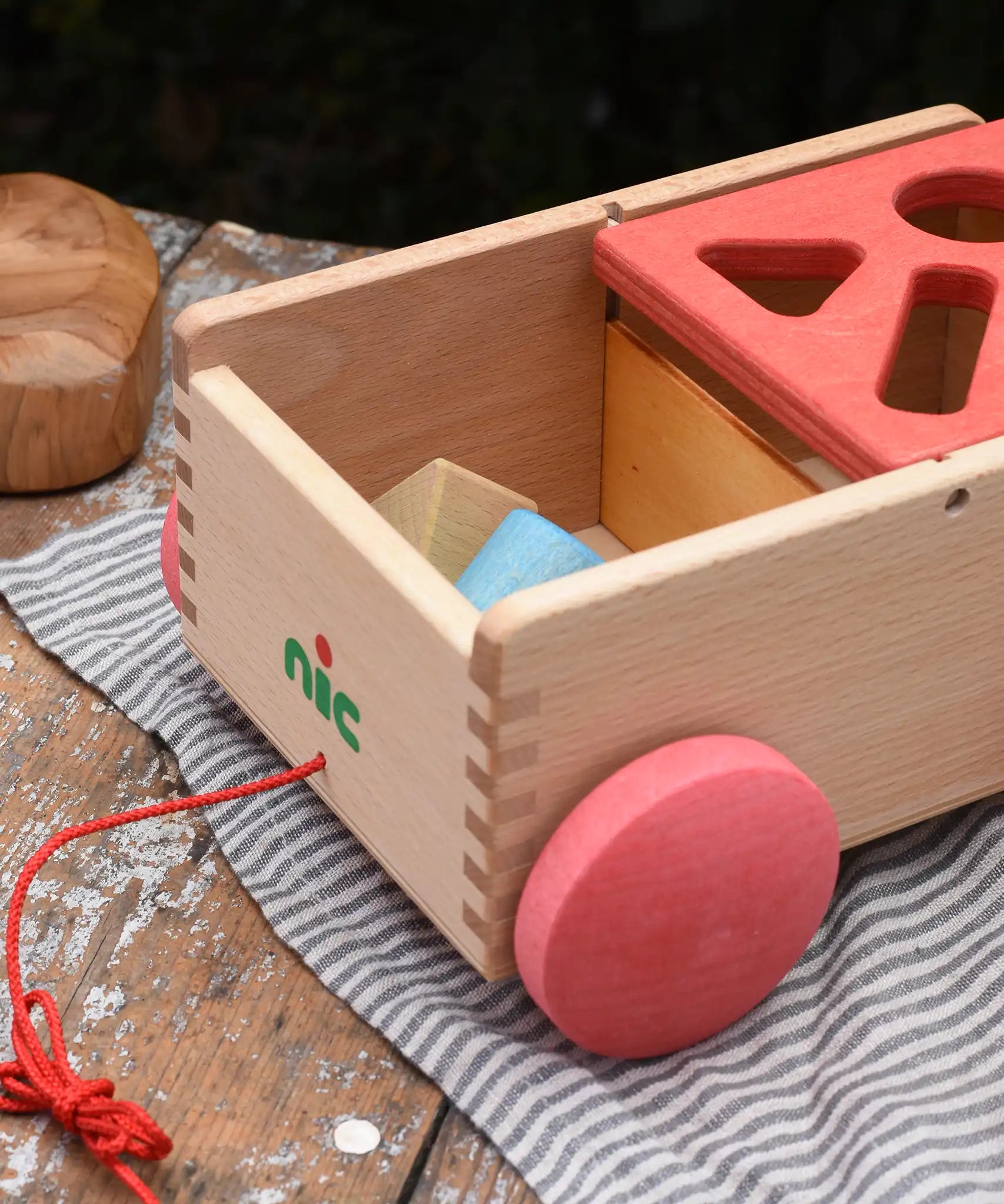 Nic wooden carriage shape sorter pull along toy shown with the blocks inside in the uncovered part. 