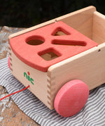 Close up of the shaped slots on the red lid of the Nic wooden carriage shape sorter pull along toy. 