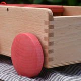 Close up of the red wooden wheels on the Nic wooden carriage shape sorter pull along toy. 8 wooden blocks in various shapes and colours. 