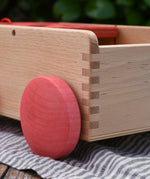 Close up of the red wooden wheels on the Nic wooden carriage shape sorter pull along toy. 8 wooden blocks in various shapes and colours. 