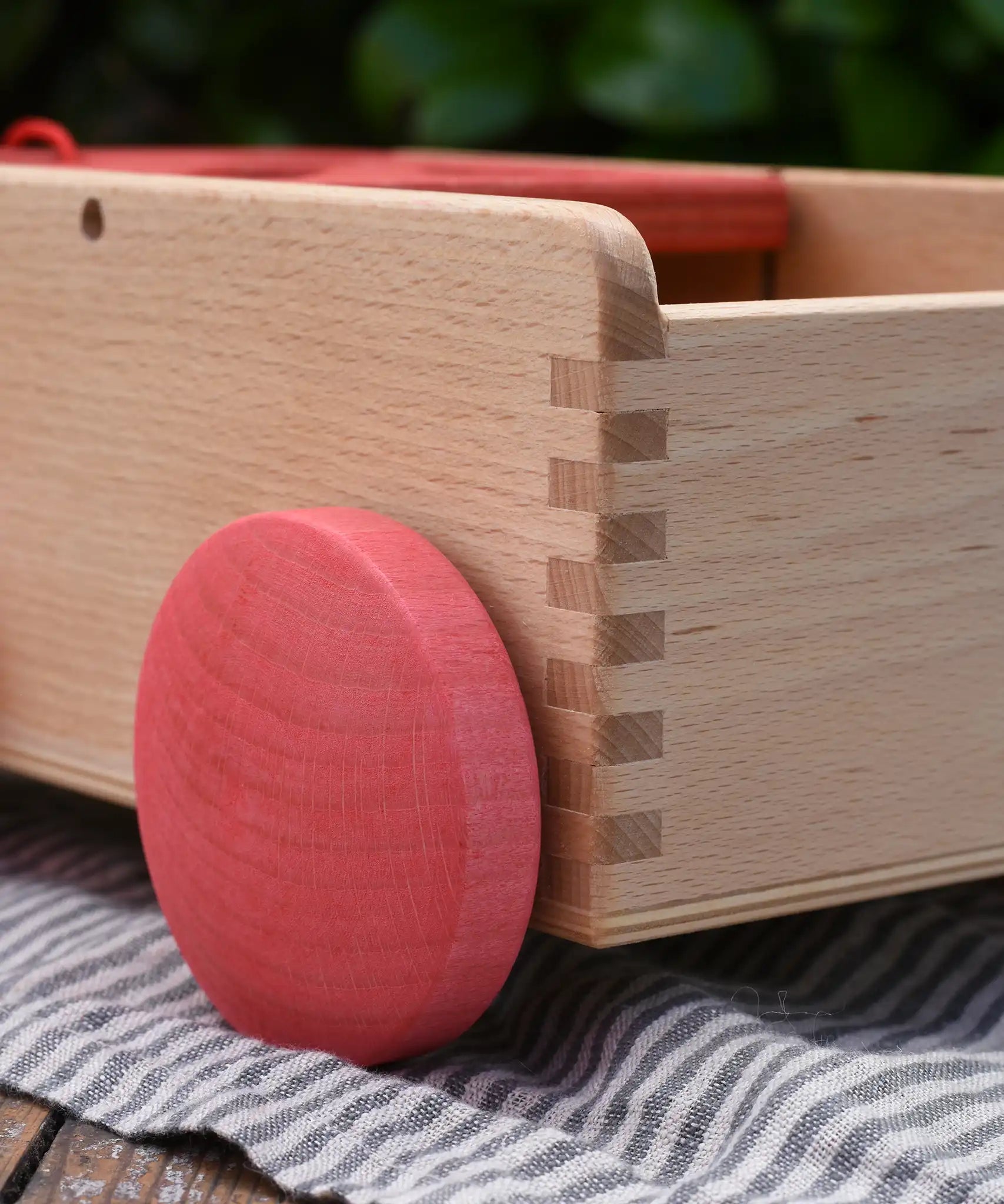 Close up of the red wooden wheels on the Nic wooden carriage shape sorter pull along toy. 8 wooden blocks in various shapes and colours. 