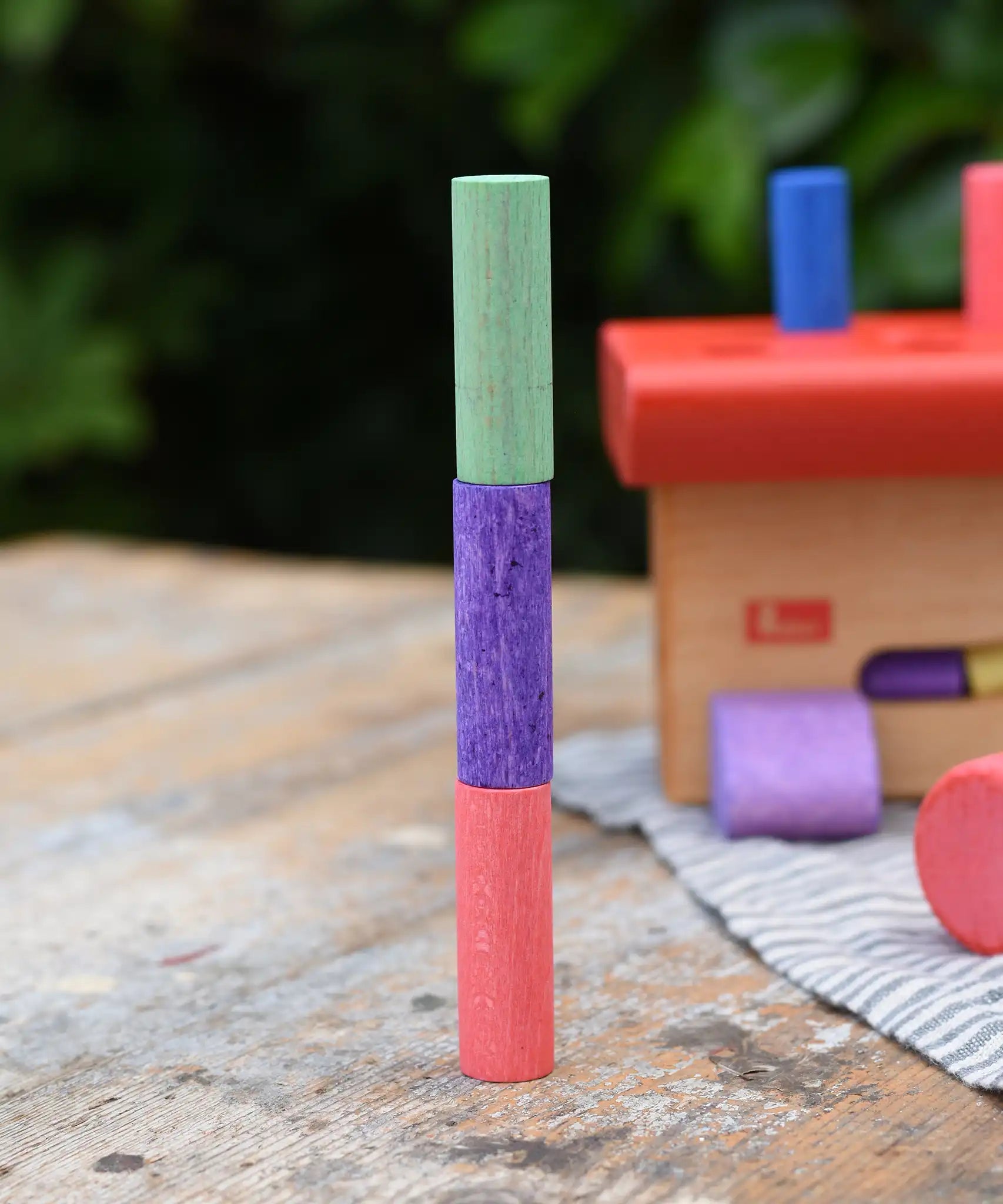 Three cylinder blocks from the Nic Walter bio organic wooden pounding bench children's toy stacked on top of each other.