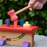Child's hand holding the hammer rom the Nic Walter bio organic wooden pounding bench children's toy.