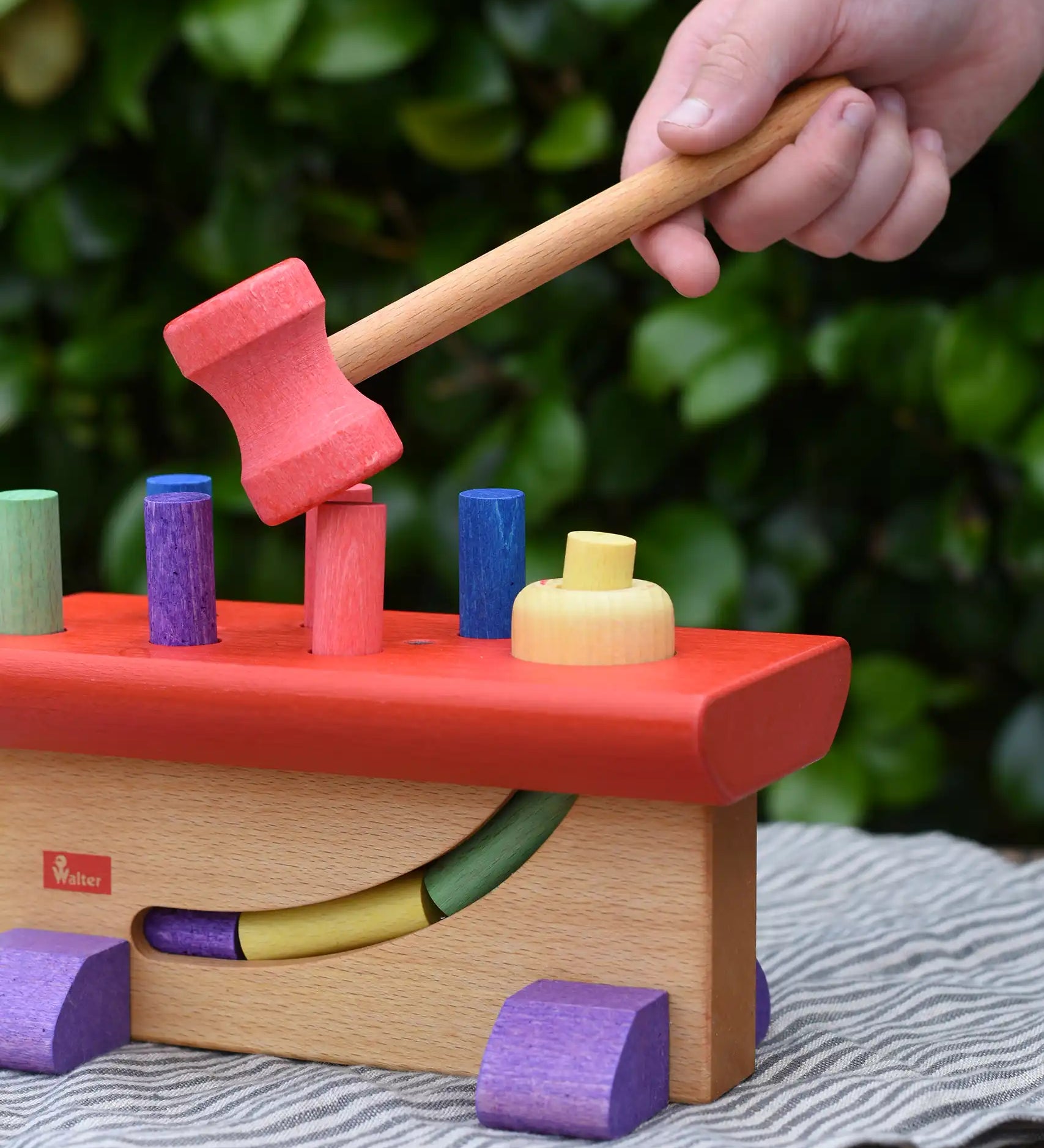 Child's hand holding the hammer rom the Nic Walter bio organic wooden pounding bench children's toy.