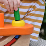Close up of a child placing a cylinder shaped block into the slot in the Nic wooden pounding bench hammering toy.