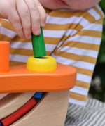 Close up of a child placing a cylinder shaped block into the slot in the Nic wooden pounding bench hammering toy.