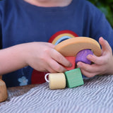 Child playing with the Nic Toys wooden threaded shape sorter. Wooden disk with a keyhole shape cut out in the middle with a piece of thread feeding through different coloured blocks in different coloured shapes.