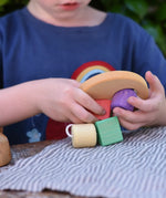 Child playing with the Nic Toys wooden threaded shape sorter. Wooden disk with a keyhole shape cut out in the middle with a piece of thread feeding through different coloured blocks in different coloured shapes.