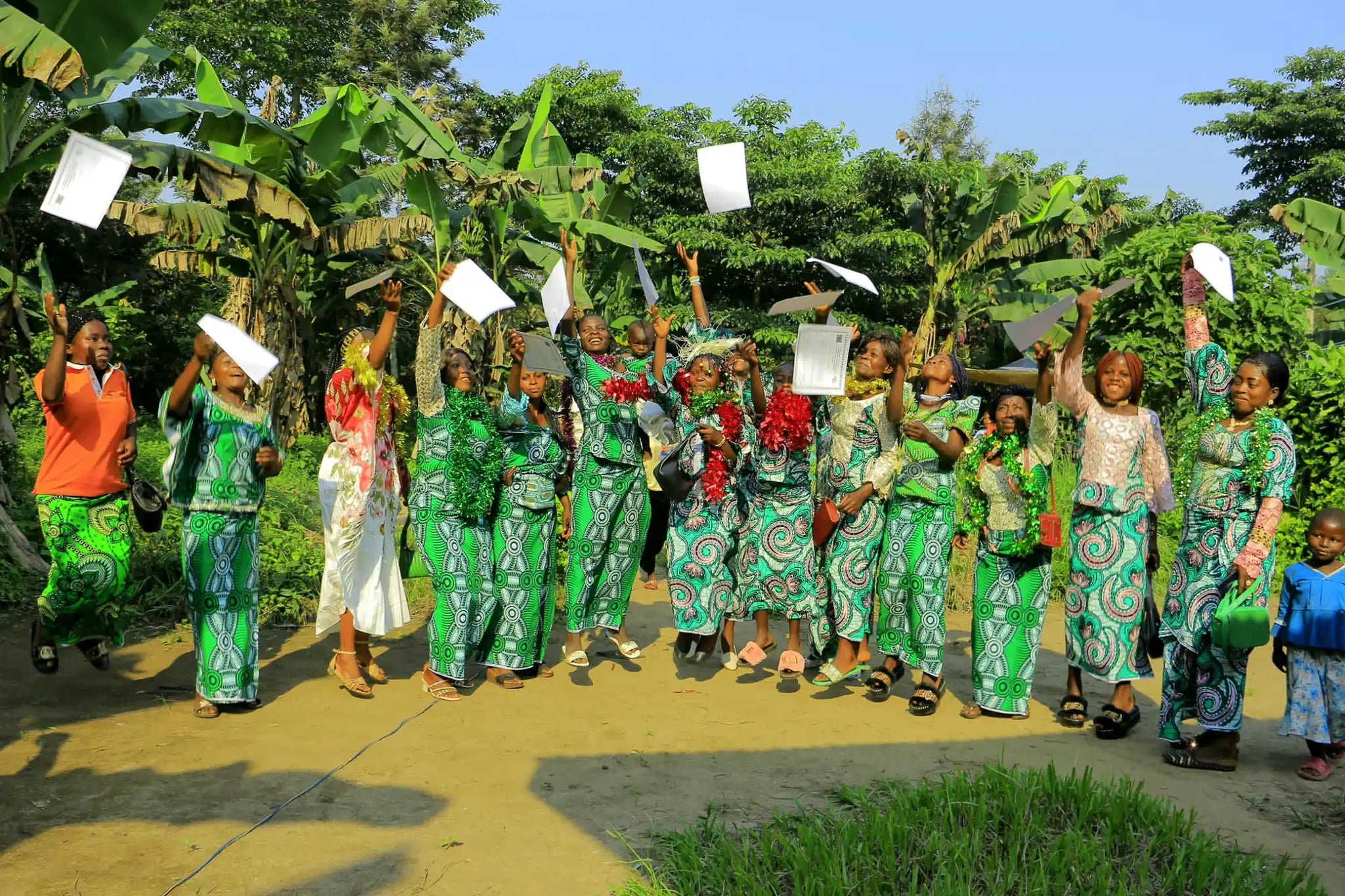 Group of cacao farm workers and farmers throwing certificates in the air in celebration. 