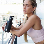 Woman leaning on a railing holding a 500ml One Green Bottle Tough metal drinks bottle