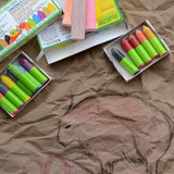 OkoNorm 12 stubby beeswax crayons placed next to cave wall themed drawings on brown paper. 
