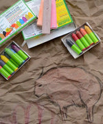 OkoNorm 12 stubby beeswax crayons placed next to cave wall themed drawings on brown paper. 
