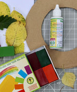 OkoNorm solvent free all purpose craft glue placed on a table amongst other craft supplies.