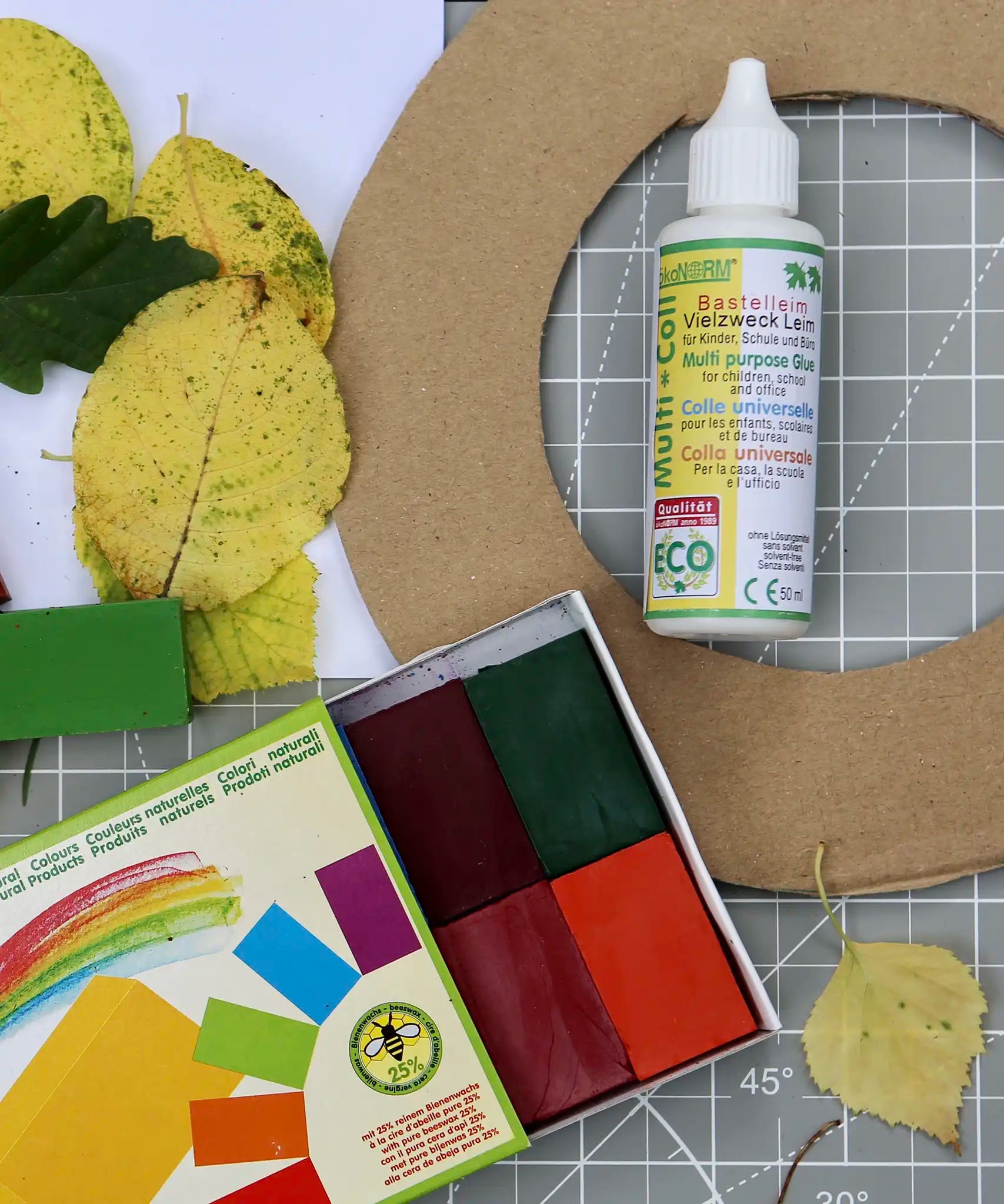 OkoNorm solvent free all purpose craft glue placed on a table amongst other craft supplies.